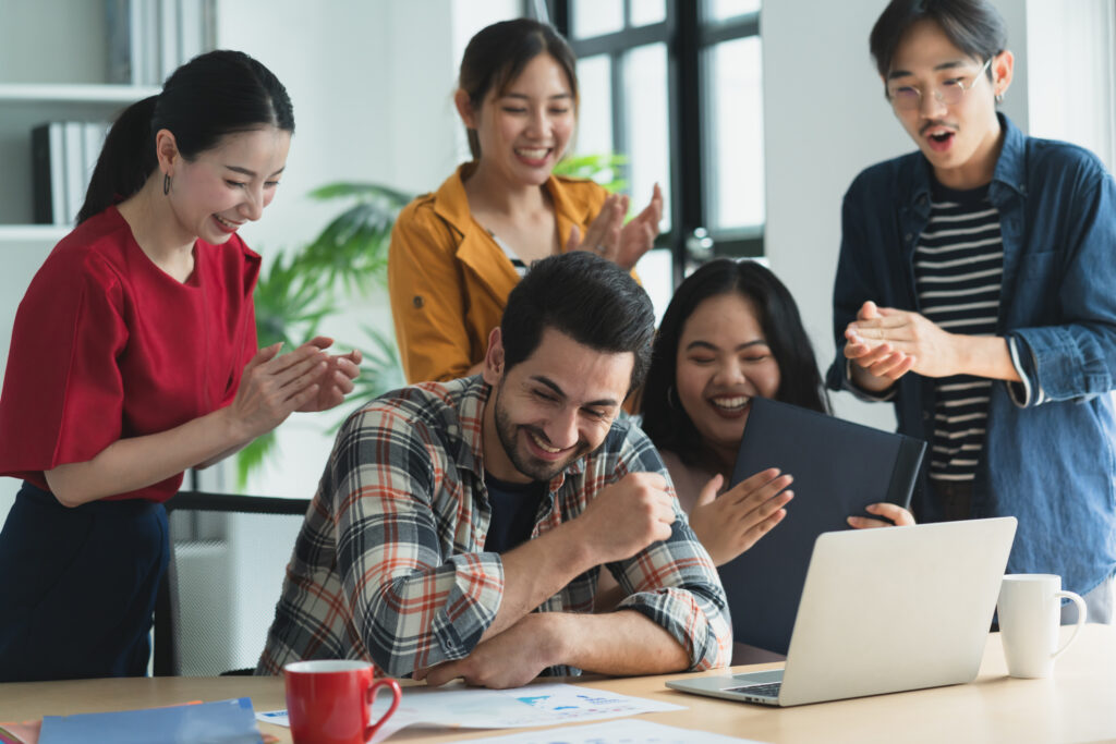 trendy hipster asian creative friend smiling while sitting casual meeting with group friends coworker are working new success project while using laptop computers digital